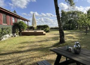 a picnic table in a yard with an umbrella at Holiday Home By Limfjord With Historic Charm in Farsø +14 photos