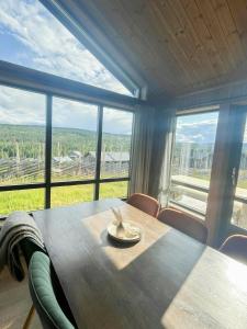 a dining room with a table and a large window at Cabin With Views Over Hafjell And Gausdal in Svingvoll