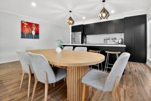 a kitchen and dining room with a wooden table and chairs at Forsyth Retreat - Modern Townhouse in Wagga Wagga +21 photos