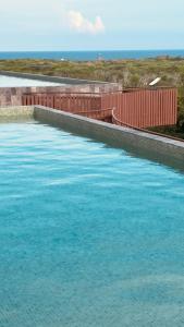 a large pool of blue water next to a fence at Jungle Guardian - Rooftop Pool & Beach Club in Zona Hotelera Tulum in Tulum