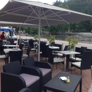 un restaurante con mesas, sillas y sombrilla en Hotel Garni Aich, en St. Blasien