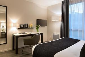 Una habitación de hotel con un escritorio y una cama. en Citadines Montmartre Paris, en París