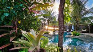 a resort swimming pool with palm trees and plants at Paua Hotel Boutique in Pipa