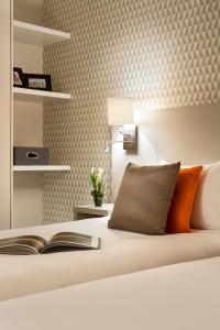 a hotel room with a white bed and white pillows at Citadines Montmartre Paris in Paris