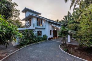una casa con una entrada para autos en frente de ella en SaffronStays Osaree, Kihim - pet-friendly pool villa perfect for a workcation, en Alibaug