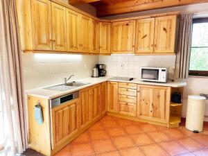 a kitchen with wooden cabinets and a sink and a microwave at Mountains Family Retreat in Rudník