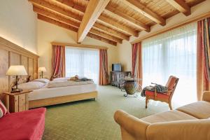 a bedroom with two beds and a chair and a couch at Arlberg Stuben - das kleine, feine Hotel in Stuben am Arlberg