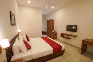 a hotel room with a bed and a television at Hotel Abaam Neil in Kumarakom