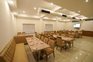 a dining room with tables and chairs and a tv at Hotel Abaam Neil in Kumarakom