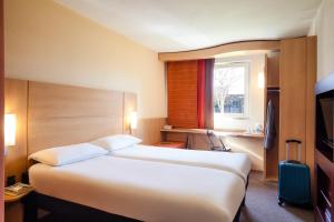 
a hotel room with two beds and a television at ibis Cardiff Centre in Cardiff
