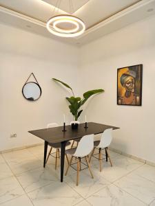 a dining room with a black table and white chairs at Résidence Jordan in Dakar
