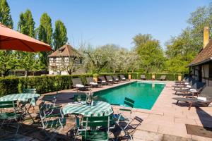 einen Pool mit Stühlen, Tischen und einem Sonnenschirm in der Unterkunft Hotel Restaurant De l'Illwald in Sélestat