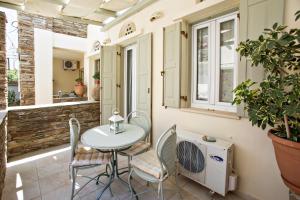 eine Terrasse mit Tisch, Stühlen und einem Waschbecken in der Unterkunft Tiniotissa Studios in Tinos