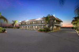 a large building with palm trees in front of it at Days Inn by Wyndham Lost Hills in Lost Hills
