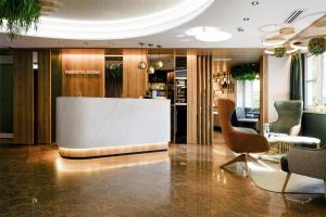 een lobby met een bar, stoelen en een tafel bij Best Western Plus Parkhotel Erding in Erding