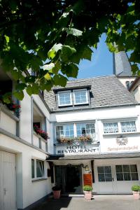 a white building with windows and flowers on it at Hotel Springiersbacher-Hof in Kröv