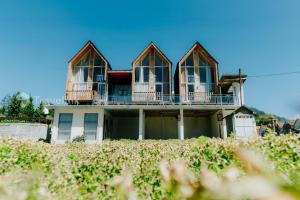 a house with four windows on top of a field at Kijang Mas By Travelink in Dieng