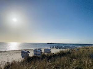 a beach with chairs and a pier in the water at Haus Larum App. 3 in Scharbeutz
