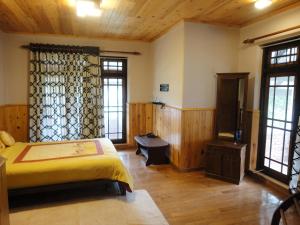 a bedroom with a bed and a desk and windows at The Hill Town Cottage in Nuwara Eliya