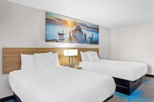 a hotel room with two beds and a painting on the wall at Days Inn by Wyndham Huntington in Pea Ridge