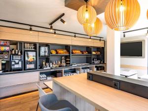 a restaurant with a bar with a tv and lights at B&B HOTEL Hannover-Laatzen in Hannover +17 photos