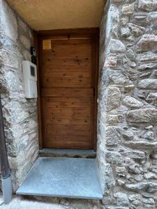 a wooden door in a stone building with a stone wall at La Caseta del Pont in Camprodon +2 photos