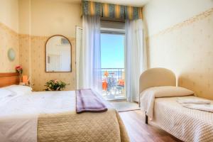 a bedroom with two beds and a large window at Hotel San Francisco Spiaggia in Rimini