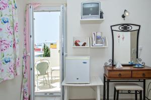 ein Zimmer mit Kühlschrank, Tisch und Spiegel in der Unterkunft Tiniotissa Studios in Tinos