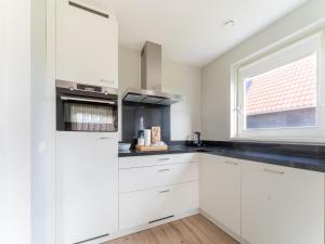 Una cocina blanca con gabinetes blancos y una ventana. en Holiday Home near Scherpenisse Beach, en Scherpenisse