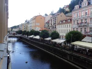 a river in the middle of a city with buildings at Apartments Paderewski in Karlovy Vary