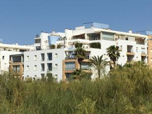 ein weißes Gebäude mit Palmen davor in der Unterkunft Espectacular Atico Frente Al Mar in Isla del Moral