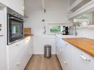 a kitchen with white cabinets and a wooden counter top at 4 person holiday home in Præstø in Præstø