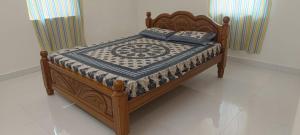 a wooden bed with a quilt on it in a room at Beverly Dinesh Homestay in Tiruvannāmalai