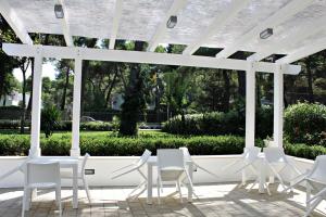 un groupe de chaises blanches sous une pergola blanche dans l'établissement Il Melograno B&B, à Castellaneta Marina