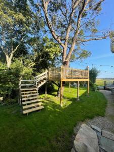 a wooden deck with a staircase next to a tree at The Nest bed and garden in Varberg