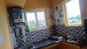 a kitchen with a sink and two windows at Beverly Dinesh Homestay in Tiruvannāmalai