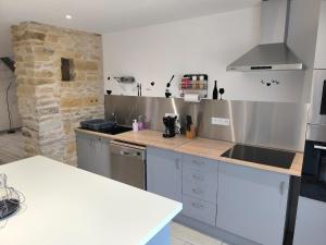 a kitchen with stainless steel appliances and a stone wall at Gîte des castors in Harricourt