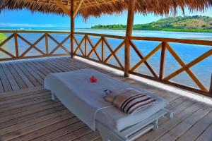 a bed on a deck with a view of the water at Villa SAHONDRA in Nosy Be