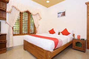 a bedroom with a bed with red pillows and a window at AVERA Heritage Homestay in Thekkady