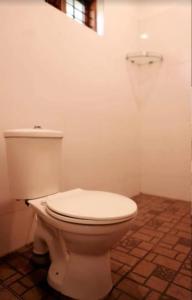 a white toilet in a bathroom with a basketball hoop at AVERA Heritage Homestay in Thekkady