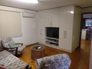 a living room with a tv and a couch and chairs at Inlet Side Eden in Inverloch +9 photos