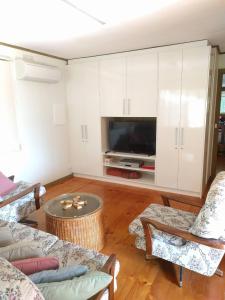 a living room with white cabinets and a flat screen tv at Inlet Side Eden in Inverloch