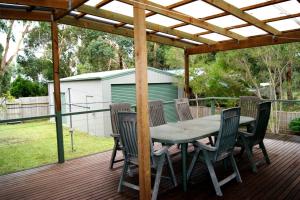 a wooden table and chairs on a deck with a pergola at Inlet Side Eden in Inverloch