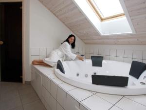 a woman sitting on a bath tub in a bathroom at 10 person holiday home in Rødby-By Traum in Kramnitse