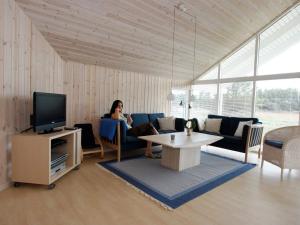 a woman sitting on a couch in a living room at 10 person holiday home in Rødby-By Traum in Kramnitse +17 photos