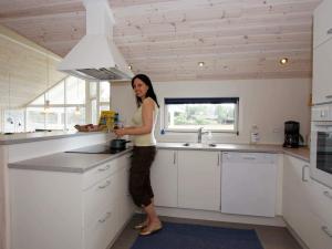 a woman standing in a kitchen preparing food at 10 person holiday home in Rødby-By Traum in Kramnitse
