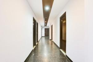 an empty hallway with white walls and floors and black doors at Hotel O Happy Residency in New Delhi