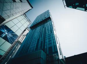 a tall glass building with a blue sky in the background at The Manchester Deansgate Hotel, by IHG in Manchester