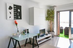 ein weißes Wohnzimmer mit einem Tisch und einem TV in der Unterkunft Apartment Poris Sunrises in Poris de Abona