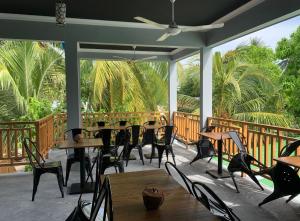 a porch with tables and chairs and palm trees at Rihiveli inn 